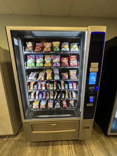 An open snack vending machine stocked with chips and bars