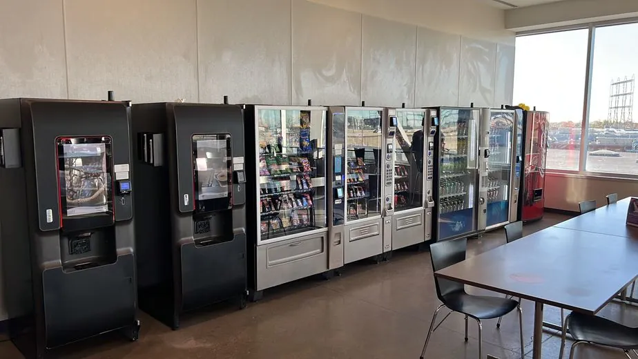 A row of snack and beverage vending machines in a bright breakroom