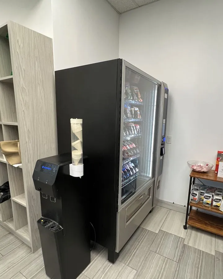 A man in a plaid shirt choosing a snack on the touchscreen of a stocked vending machine