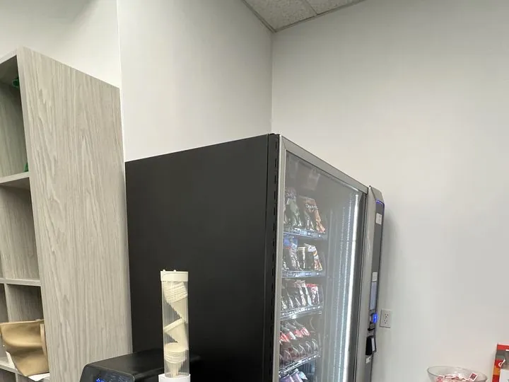 A man choosing a snack at a stocked vending machine with a touchscreen keypad