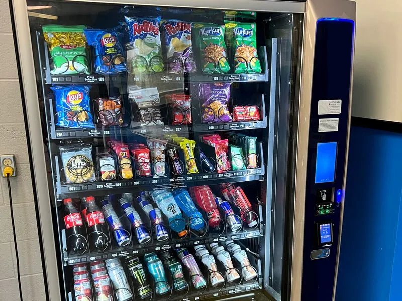 A Regional Vending machine stocked with chips, chocolate bars, soft drinks and energy drinks, with a card reader on the front panel