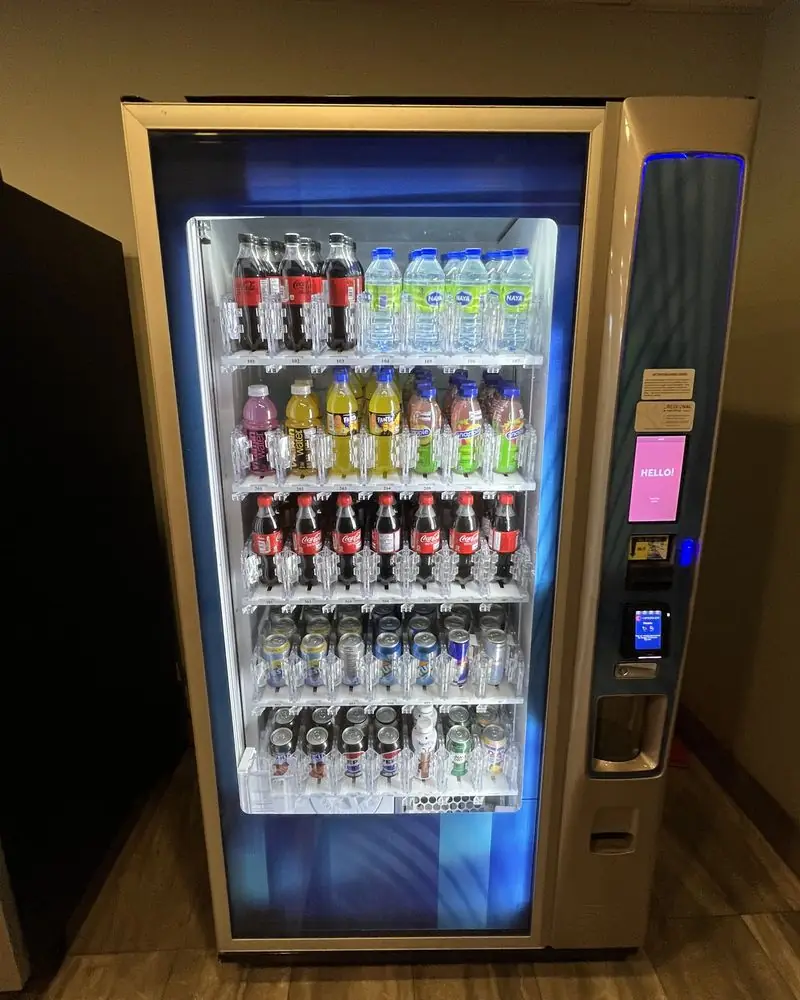 A refrigerated glass-front vending machine stocked with water, juice and soft drinks