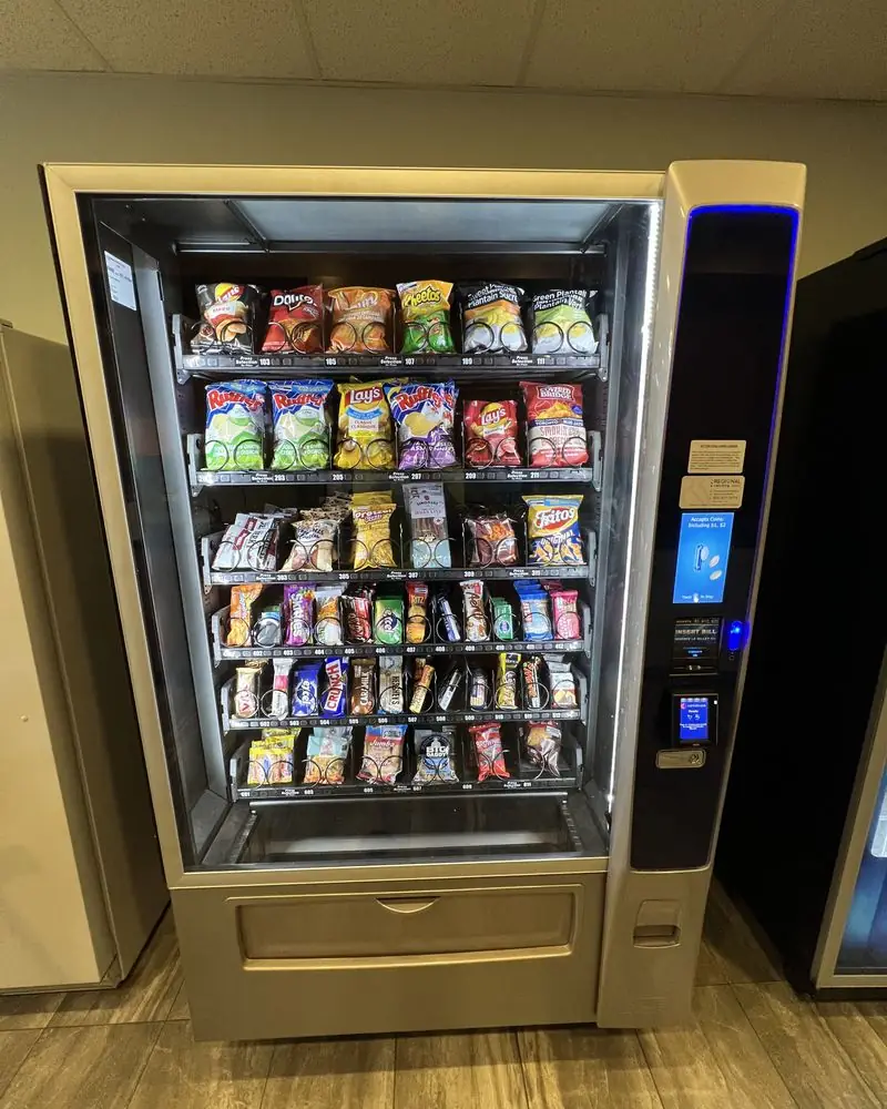 A glass-front snack vending machine stocked with chips, bars and candy