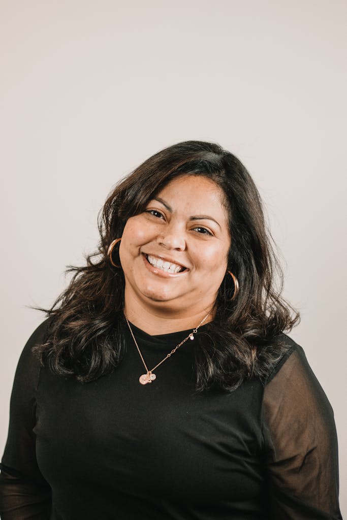 Portrait of a confident woman with a warm smile wearing a black top, ideal for business or lifestyle branding.